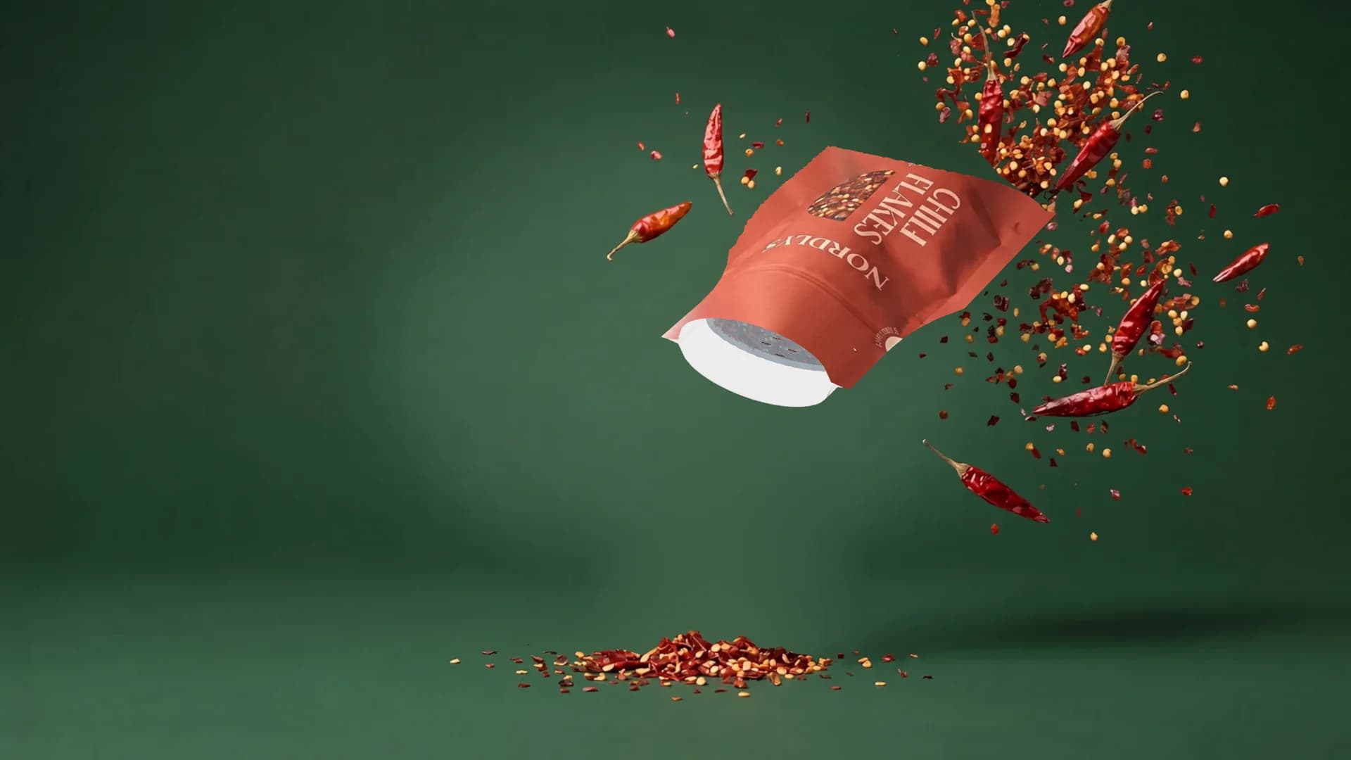 Embalagem de pimenta calabresa inclinada com a abertura para baixo; a pimenta cai através da membrana Push&Dose